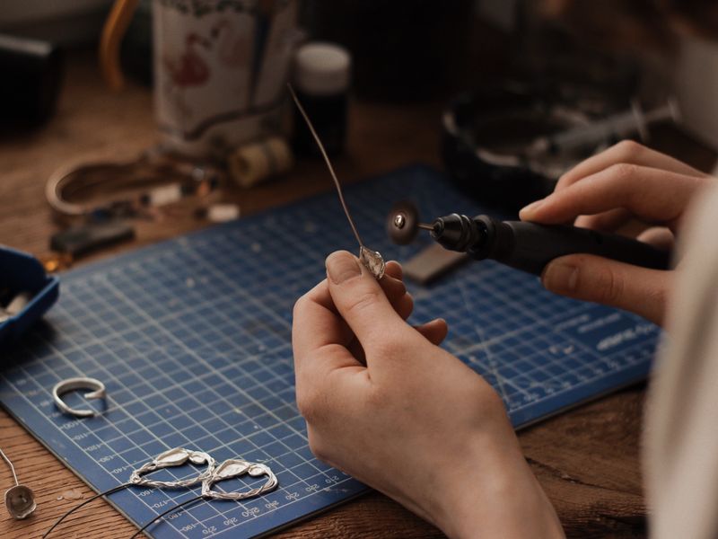 Hands polishing and finishing a 925 sterling silver jewelry piece by hand