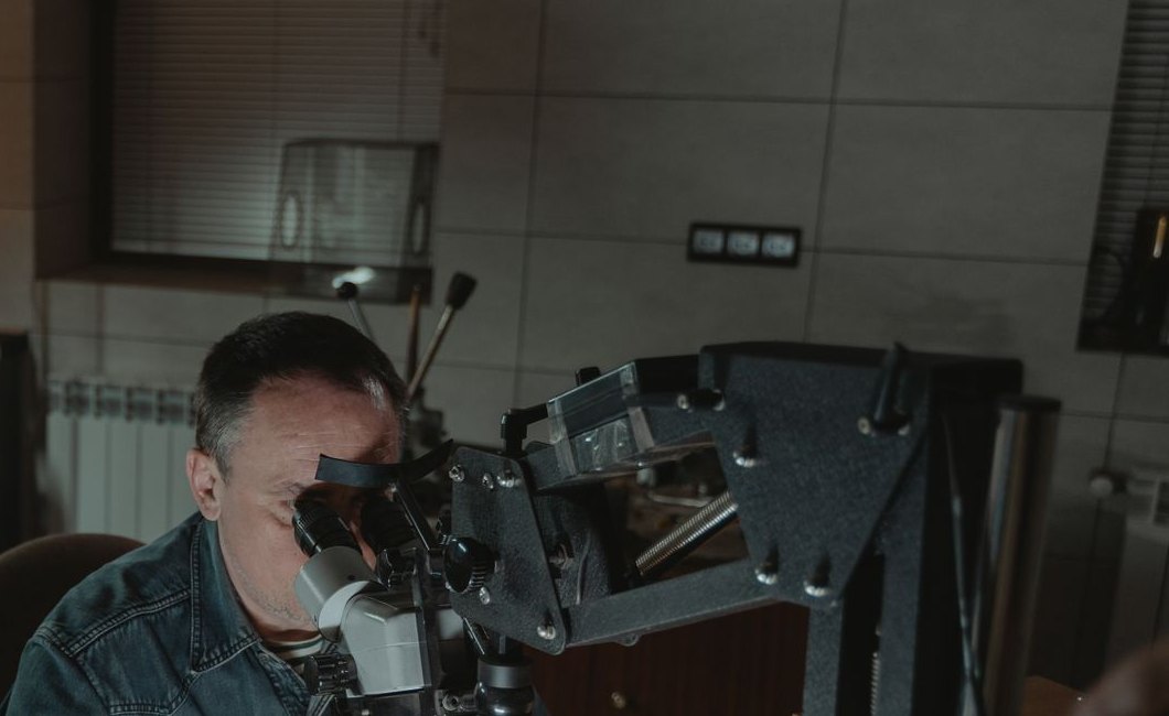Technician inspecting a finished silver jewelry piece under a microscope