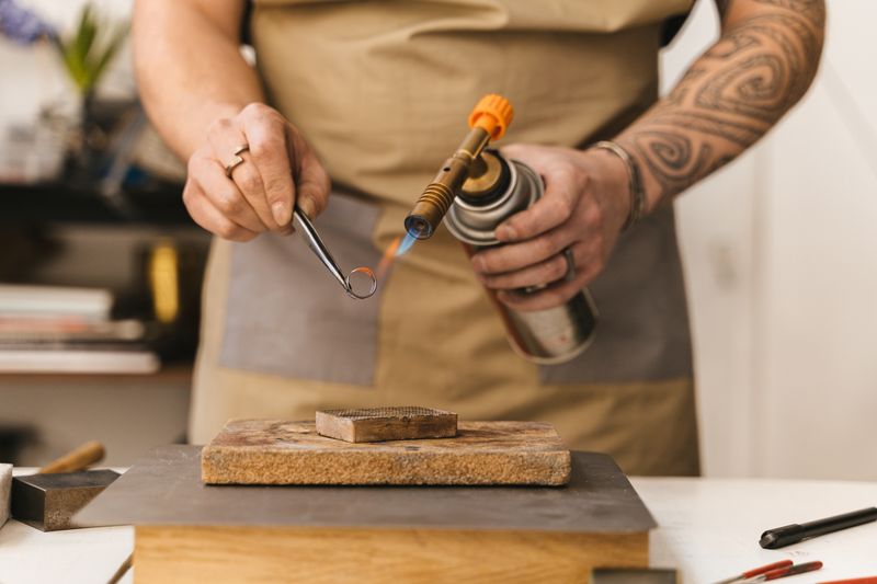 Jeweler soldering a silver ring with a torch in the workshop